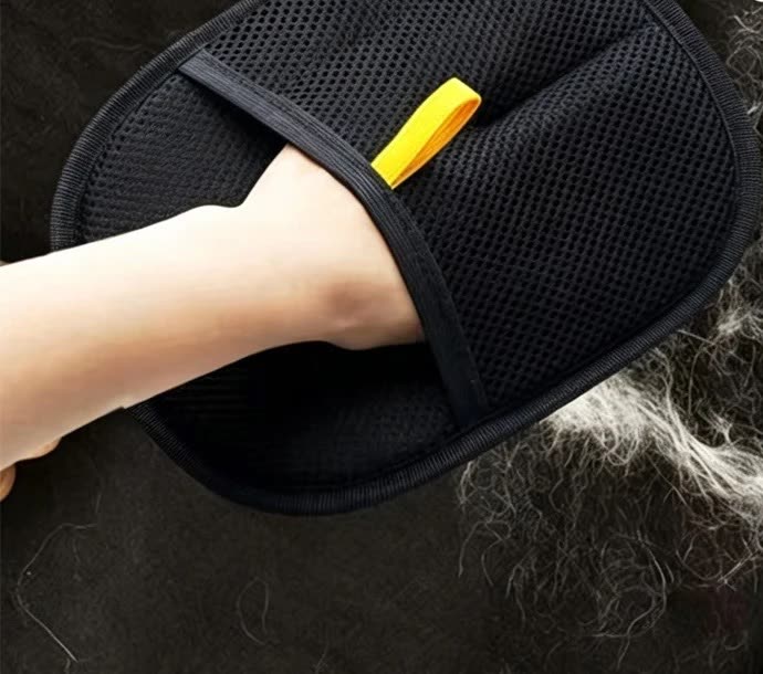 Le gant passé sur un pull noir couvert de poils clairs